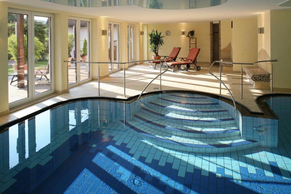 巴特阿罗尔森Landhotel Teuteberg的玻璃墙房子内的游泳池