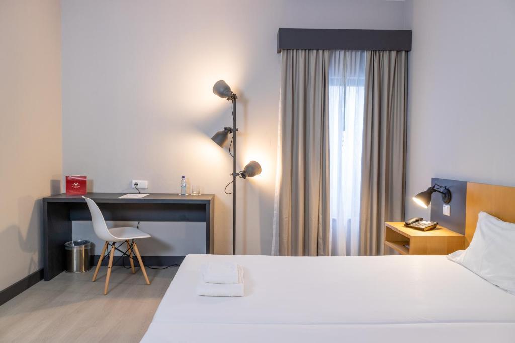 布拉加Flag Hotel Braga的酒店客房配有一张床、一张桌子和一把椅子。