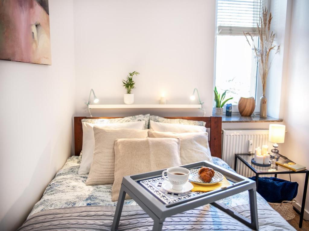 格丁尼亚Apartament Sunset Boulevard z tarasem dla 4 gości的一间卧室配有一张床铺,桌子上放着一个食物托盘