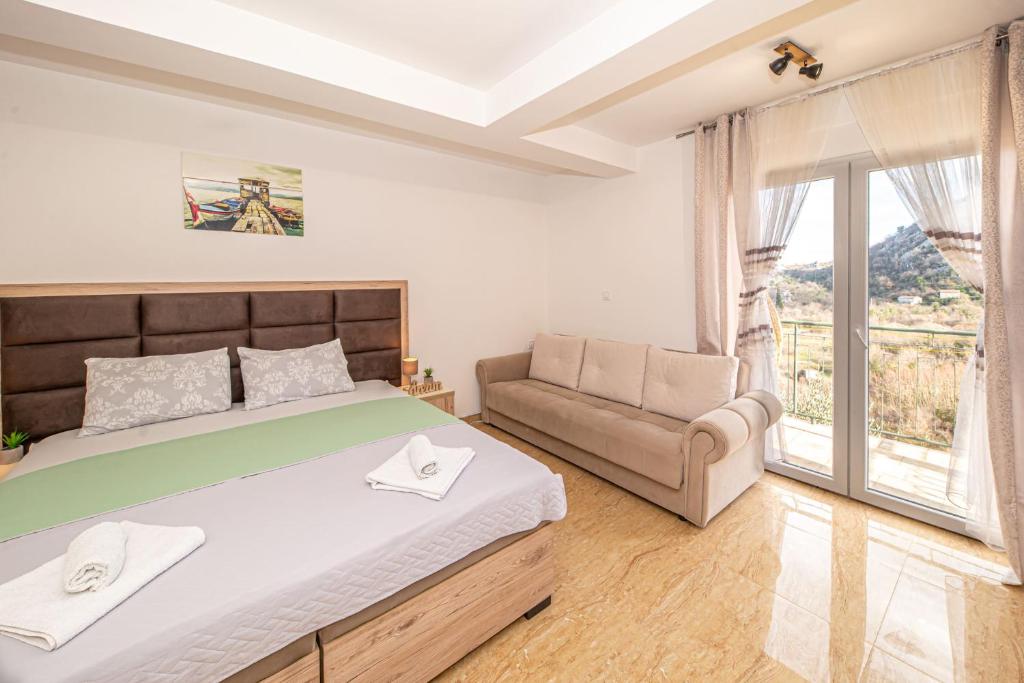 威尔帕扎Skadar lake Apartments Pajovic的一间卧室配有一张床、一张沙发和一个窗口