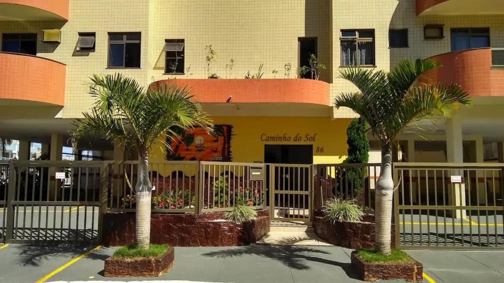 阿拉亚尔-杜卡布Apartamento na Prainha, de um quarto!的两棵棕榈树,在一座建筑前