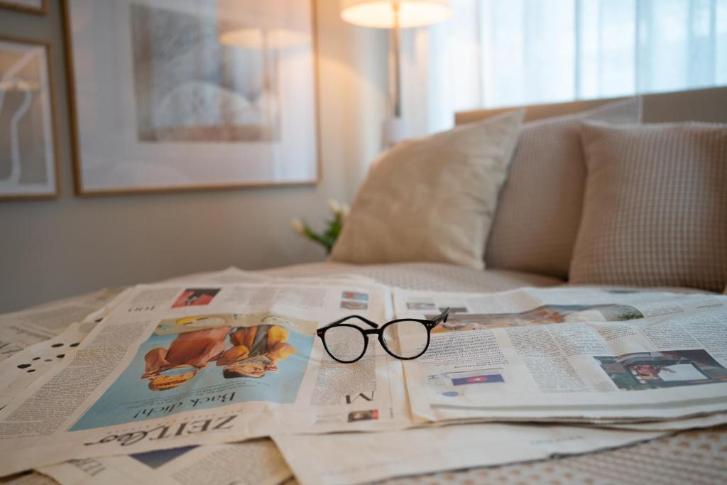 蒂门多弗施特兰德Studio-Apartment Piccolino 26的睡在床上的报纸上,放上一副眼镜