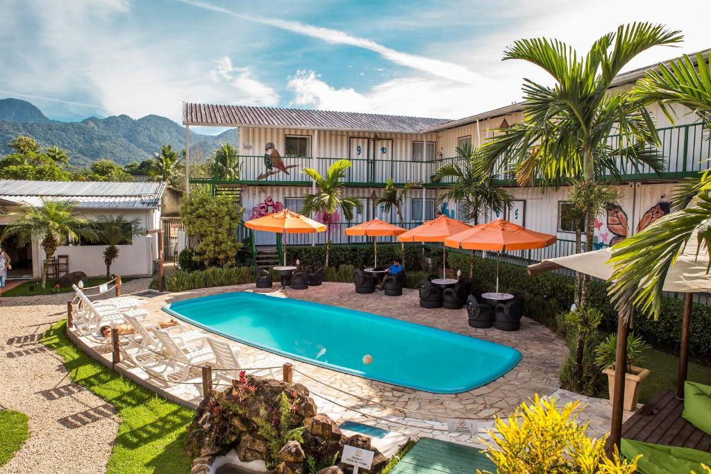 乌巴图巴Eco-Encanto Pousada的一个带游泳池和橙色遮阳伞的度假村