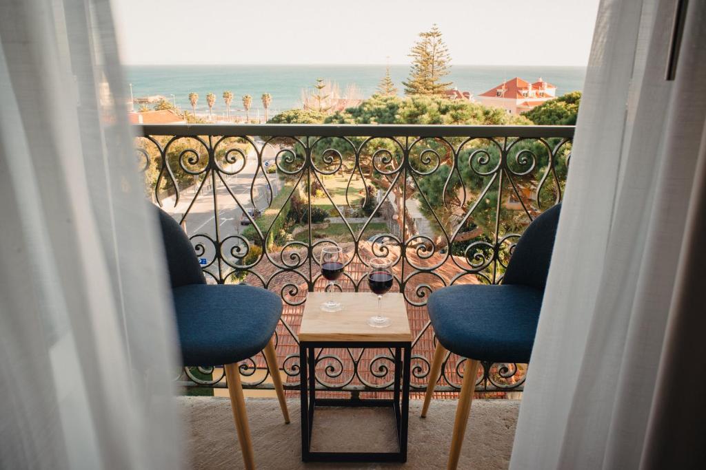 埃斯托利尔A House in Estoril - Adults Only的阳台配有两把椅子和一张桌子,享有海景。