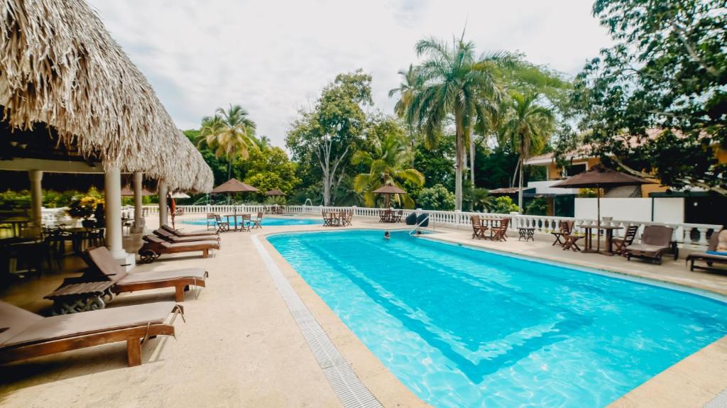 圣菲德安蒂奥基亚Hotel La Iguana de Santa fe De Antioquia的度假村的游泳池,配有椅子和遮阳伞