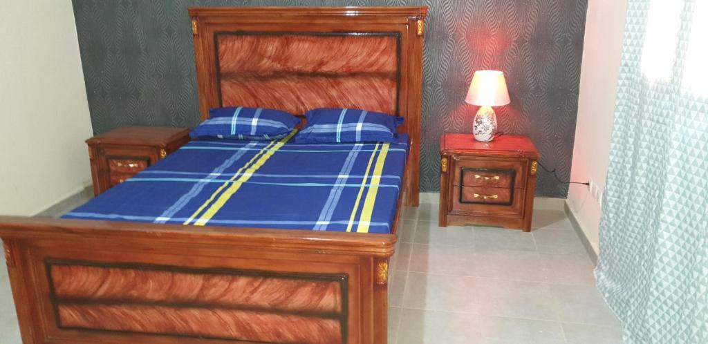 Mbaw Gou NdawAppartement meublé à MBAO的一间卧室配有一张带蓝色床单和一盏灯的床。