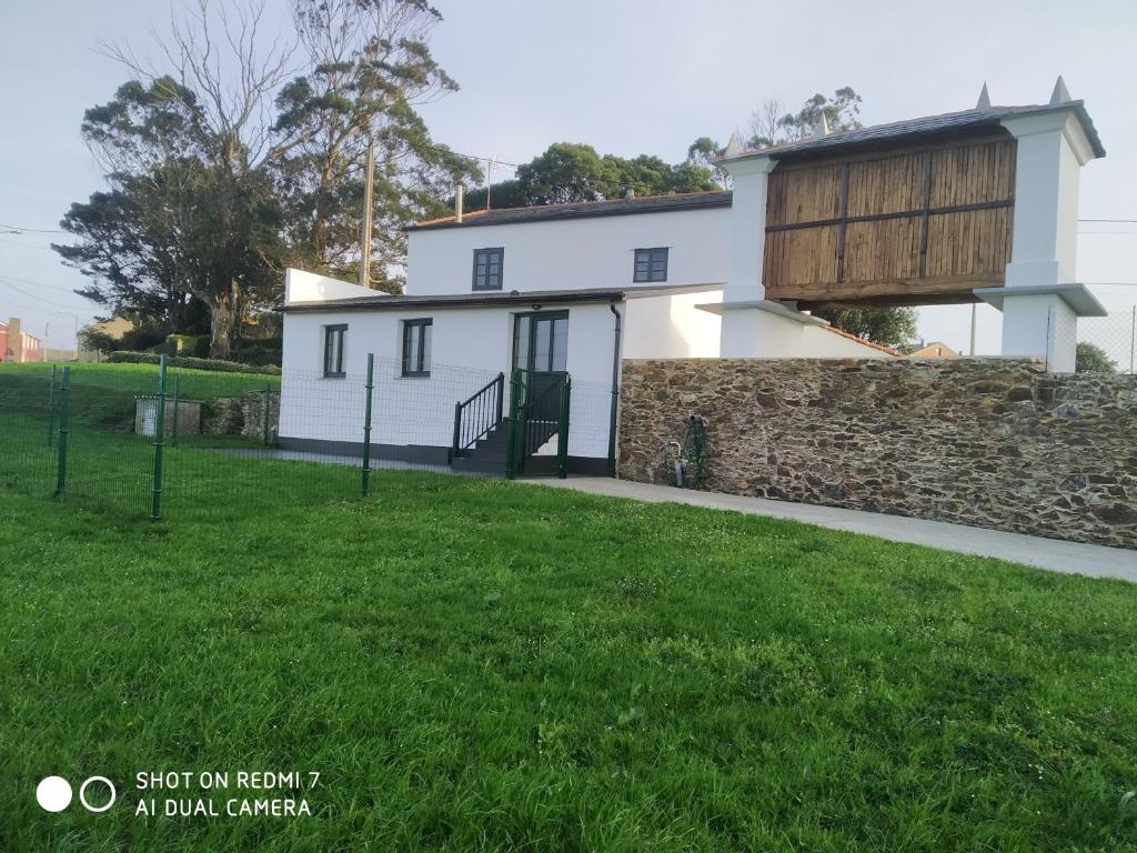 里瓦德奥A Minguxaina的白色的房子,有石墙和绿色的草地