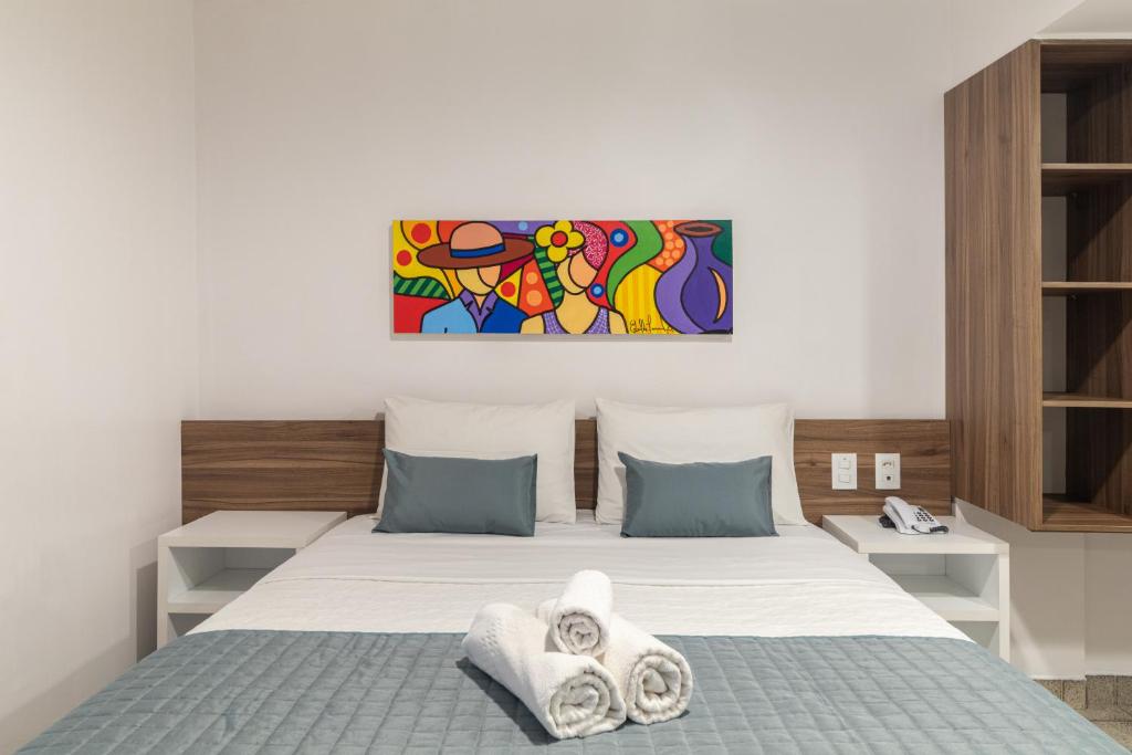 卡鲁阿鲁Citi Hotel Express Caruaru的卧室配有一张床,墙上挂有绘画作品