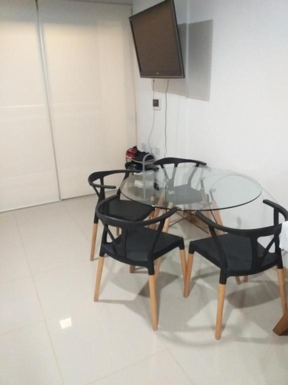 波萨达斯Monoambiente céntrico的一张玻璃桌,配有两把黑色椅子和电视
