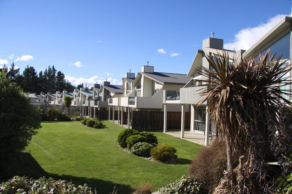 瓦纳卡Distinction Wanaka Alpine Resort的绿色草坪庭院中的一排房子