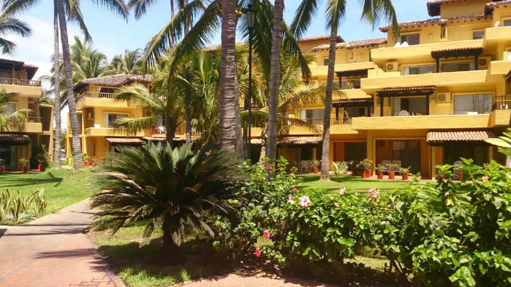 巴亚尔塔港索尔图乐斯公寓式酒店的一座棕榈树和人行道的大型黄色建筑