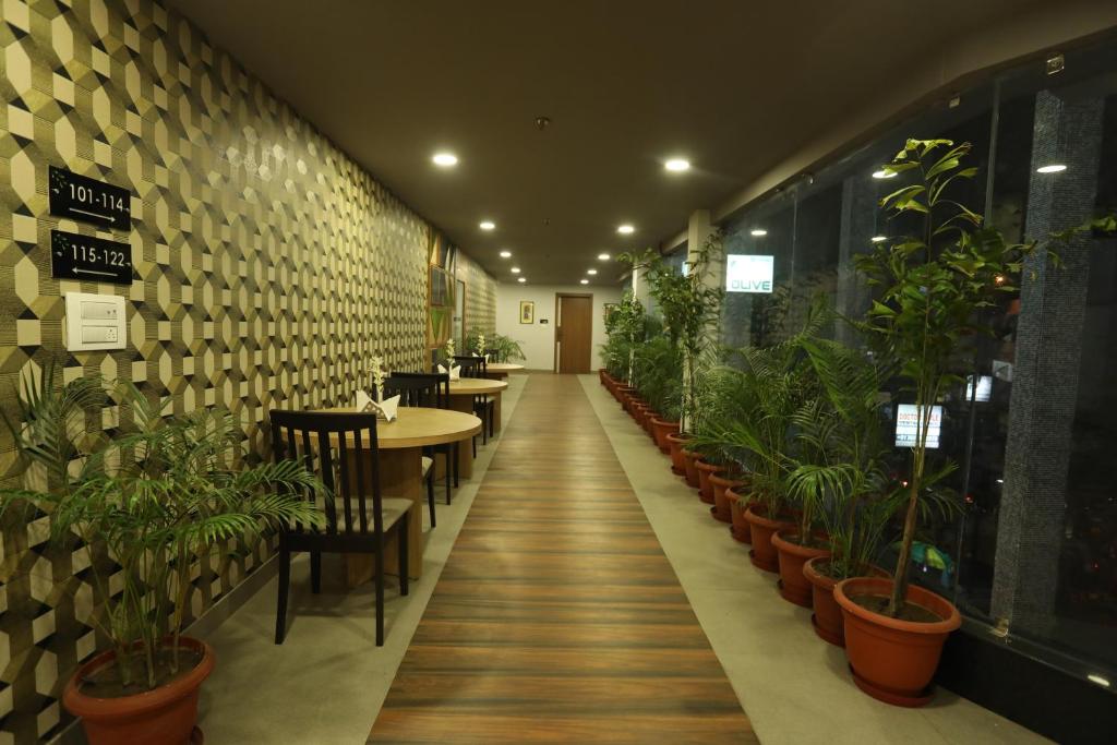 西里古里VIPs Hotel Olive的一间设有桌椅和盆栽的餐厅
