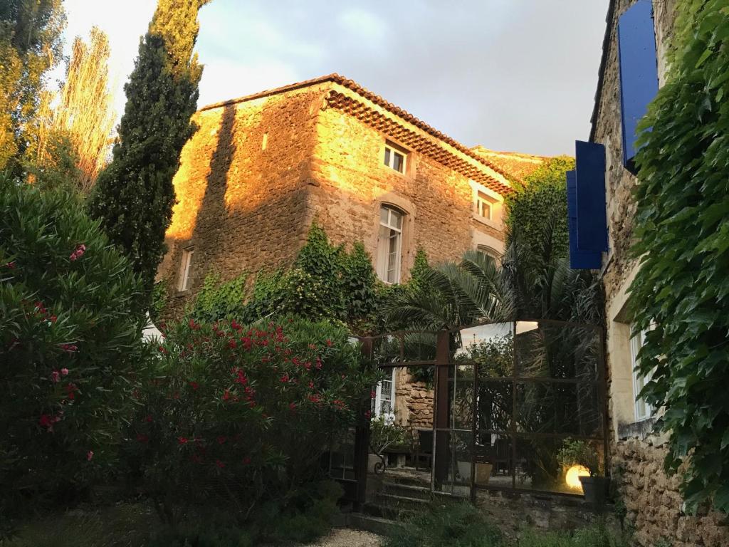 叙兹拉鲁斯Les Aiguières en Provence的前面有树木和鲜花的砖砌建筑