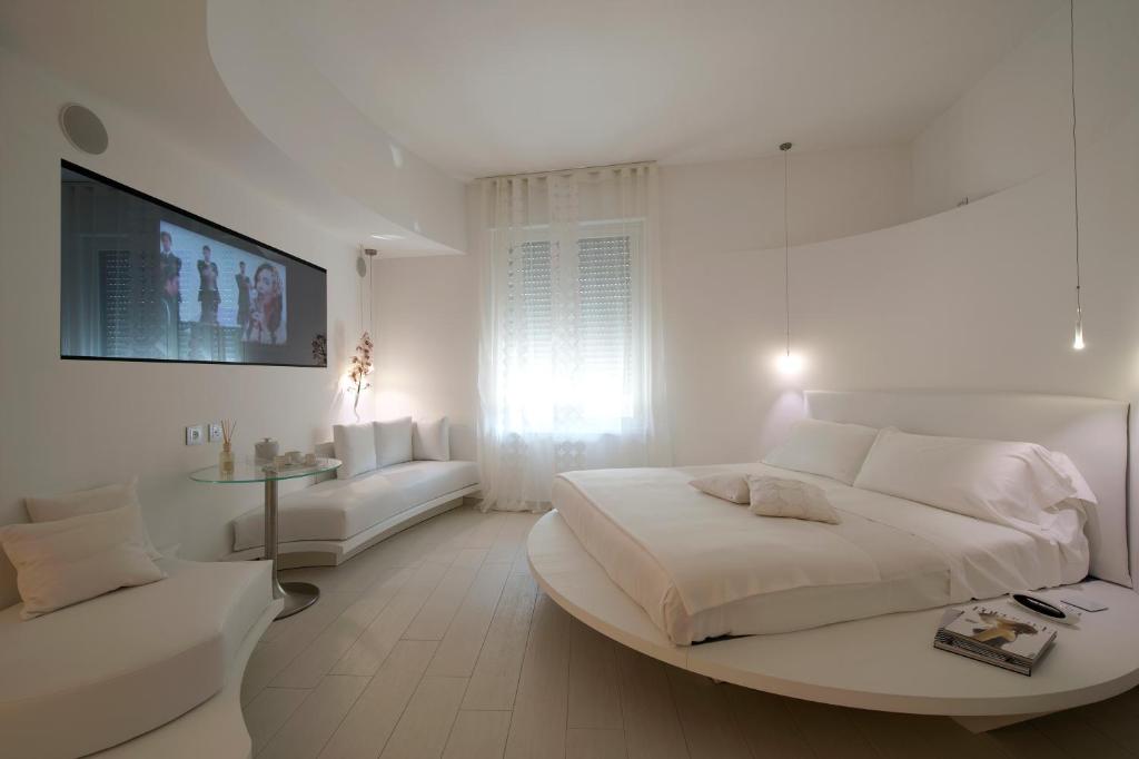 米兰多莫公寓酒店的白色卧室设有一张大床和一张沙发