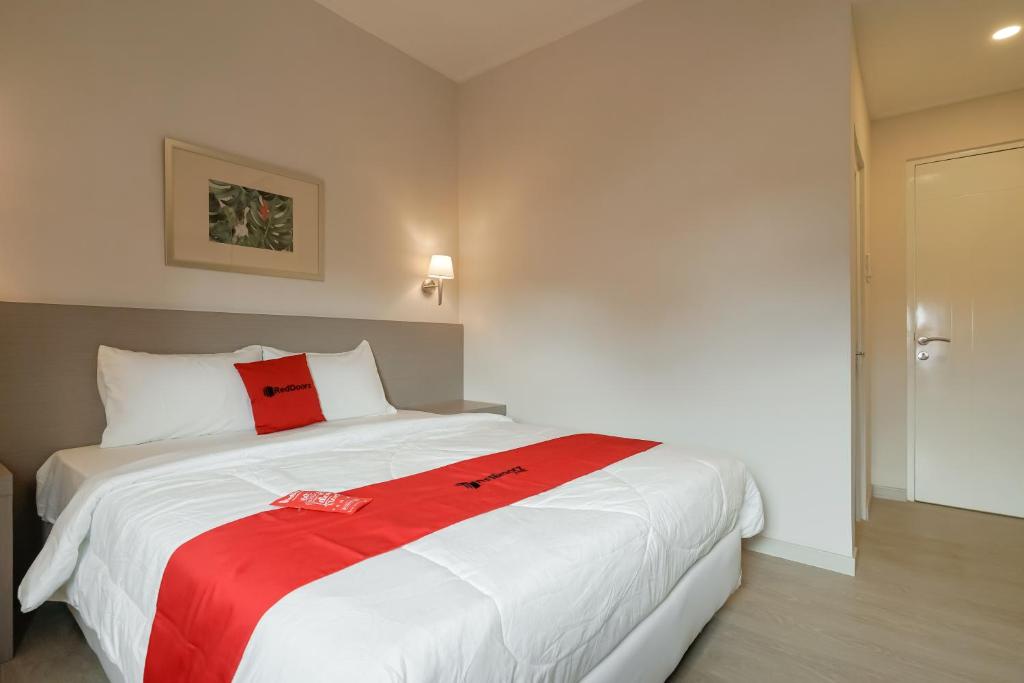 CilalungRedDoorz Syariah Plus @ BSD City的卧室配有一张大白色床和红色毯子