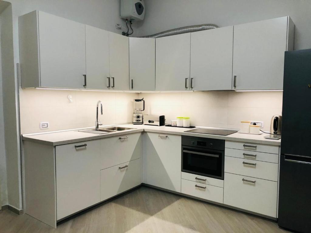 卡洛福泰Casa Novesia的厨房配有白色橱柜和黑色冰箱。