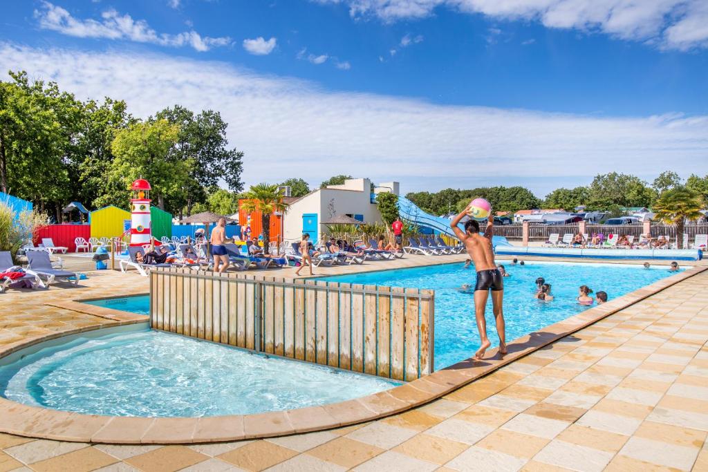 FoulerotMobil Home XXL 4 chambres - Camping Le Domaine d'Oléron的站在游乐园的游泳池里的人
