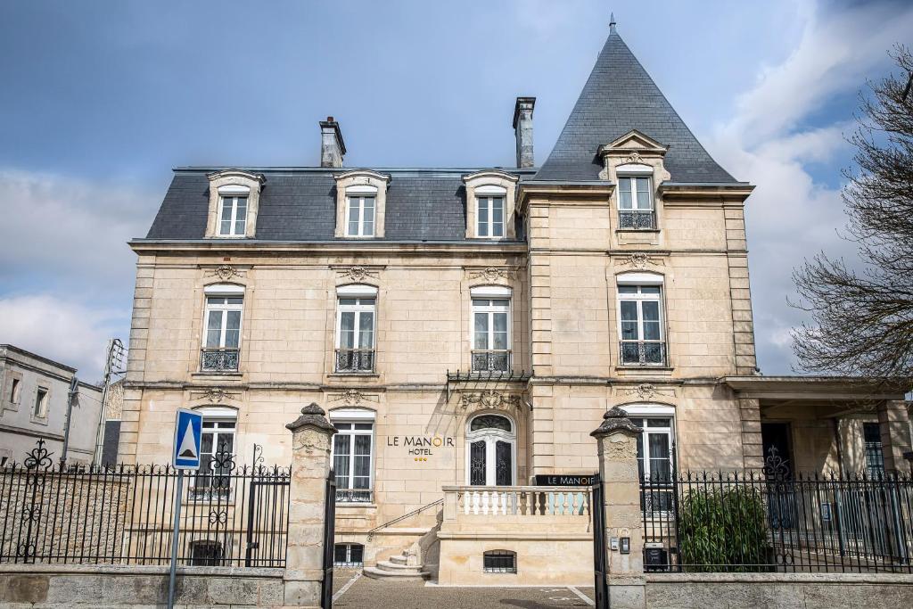 拉罗谢尔Le Manoir Hôtel的一座带黑色围栏的大型石头建筑