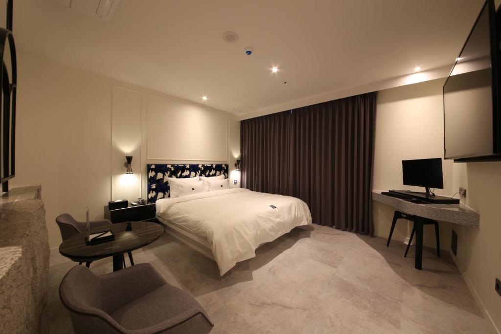 金海市Zam101 Hotel Gimhae的一间卧室配有一张床和一张带电脑的书桌