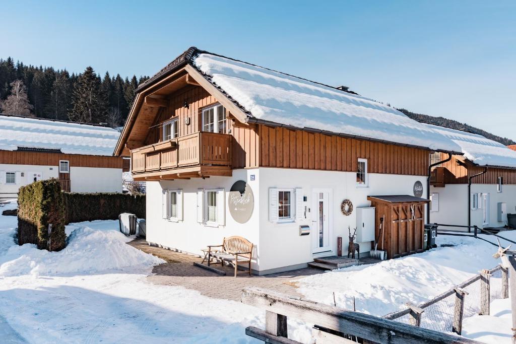 隆高地区圣玛格丽滕Pistenblick Chalet的雪中带木屋顶的房子
