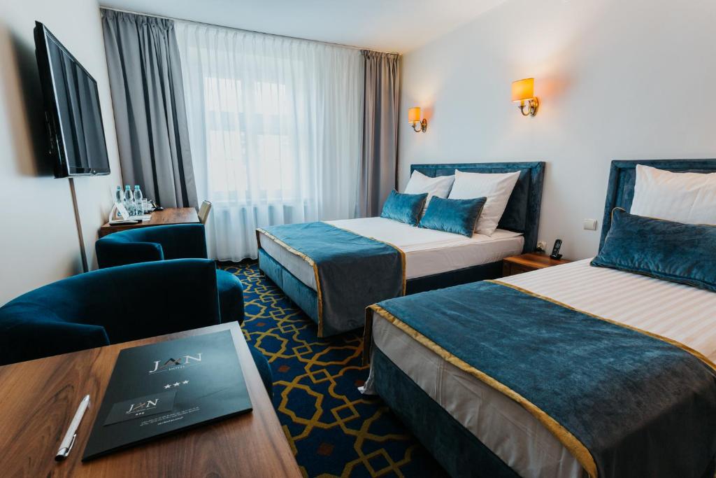 克拉科夫简恩酒店的酒店客房,配有两张床、椅子和桌子