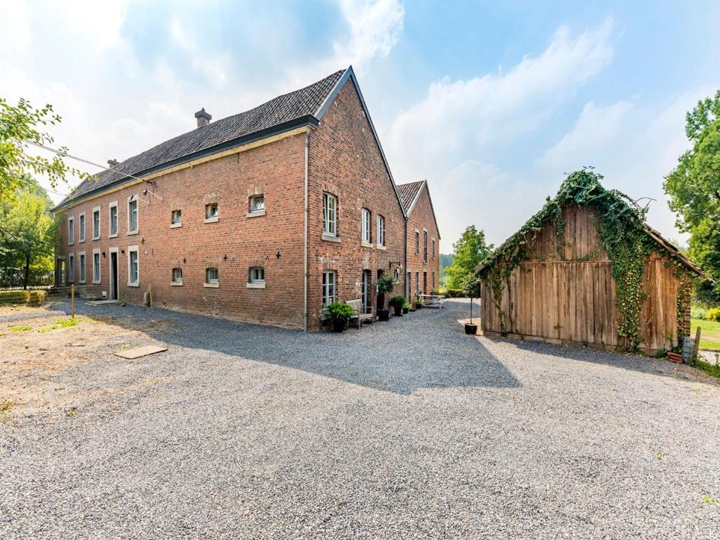 BergMagnificent Holiday Home in Sint Martens Voeren with Garden的一座大型砖砌建筑,旁边是谷仓