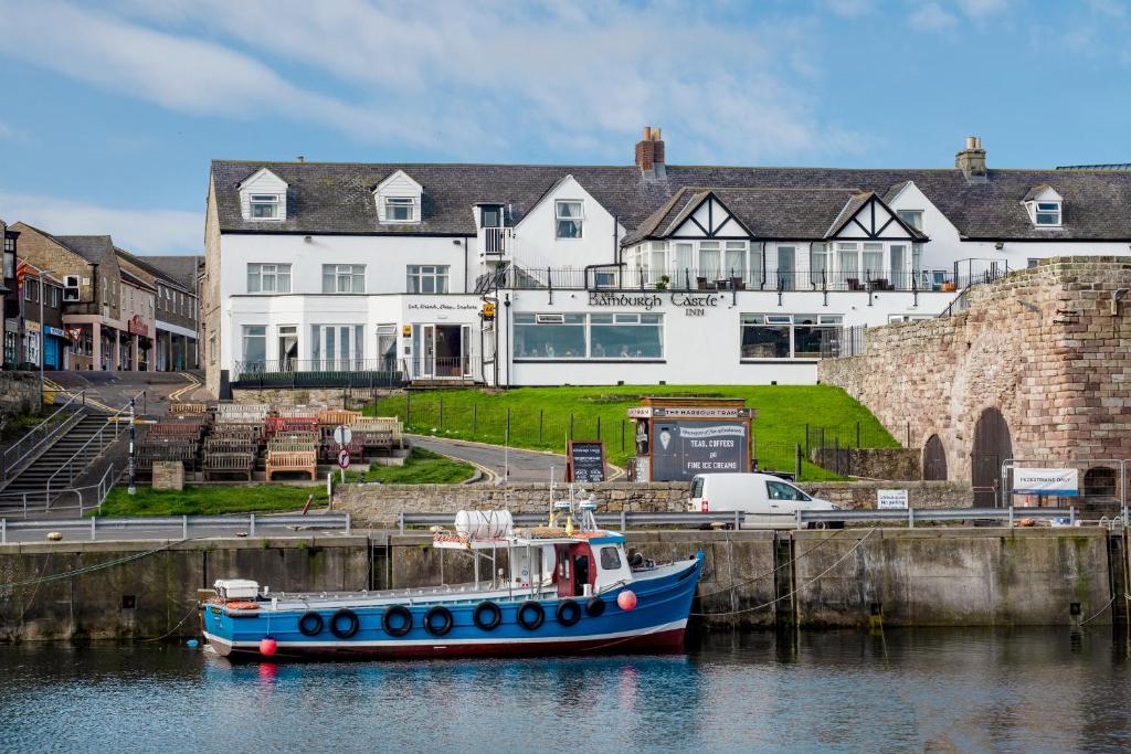 锡豪西斯The Bamburgh Castle Inn - The Inn Collection Group的船屋前水面上的蓝色船
