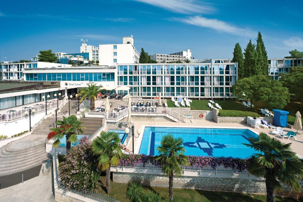 波雷奇Hotel Zorna Plava Laguna的一座带游泳池的度假村,位于一座建筑前