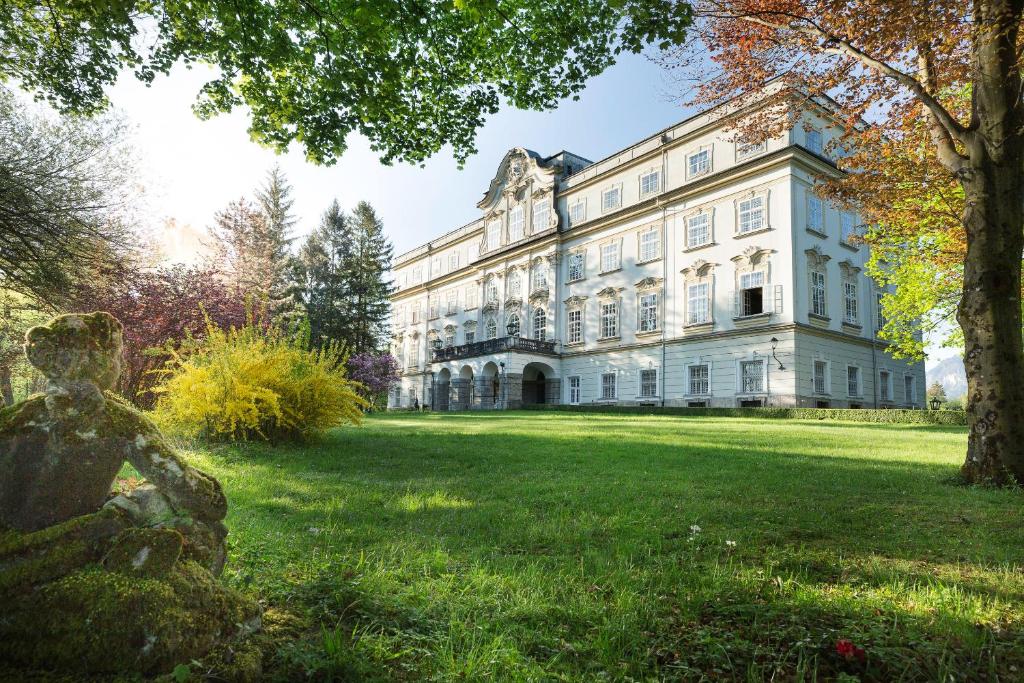 萨尔茨堡莱奥帕尔茨克龙城堡酒店的一座白色的大建筑,前面有雕像