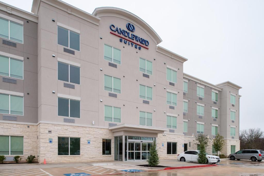 奥斯汀Candlewood Suites - Austin Airport, an IHG Hotel的停车场内停放汽车的大楼外部景观