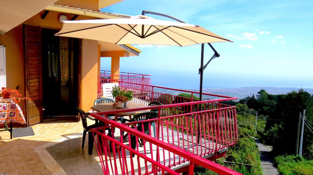 PuntalazzoCasa La Vigna的阳台配有桌子和雨伞。