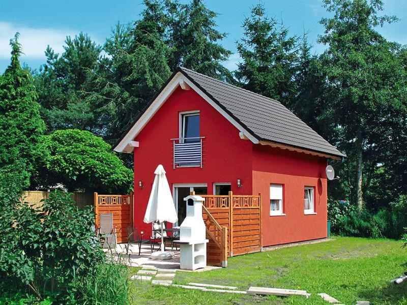 奥斯特西巴德钦诺维茨Holiday home in Zinnowitz (Seebad) 33031的红色的房子,配有雨伞和桌子