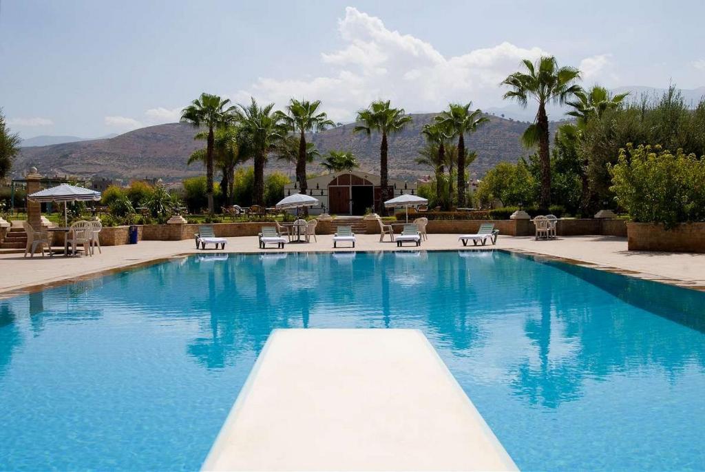 贝尼迈拉勒贝尼迈拉勒橄榄树瀑布酒店的一个带椅子和遮阳伞的大型蓝色游泳池