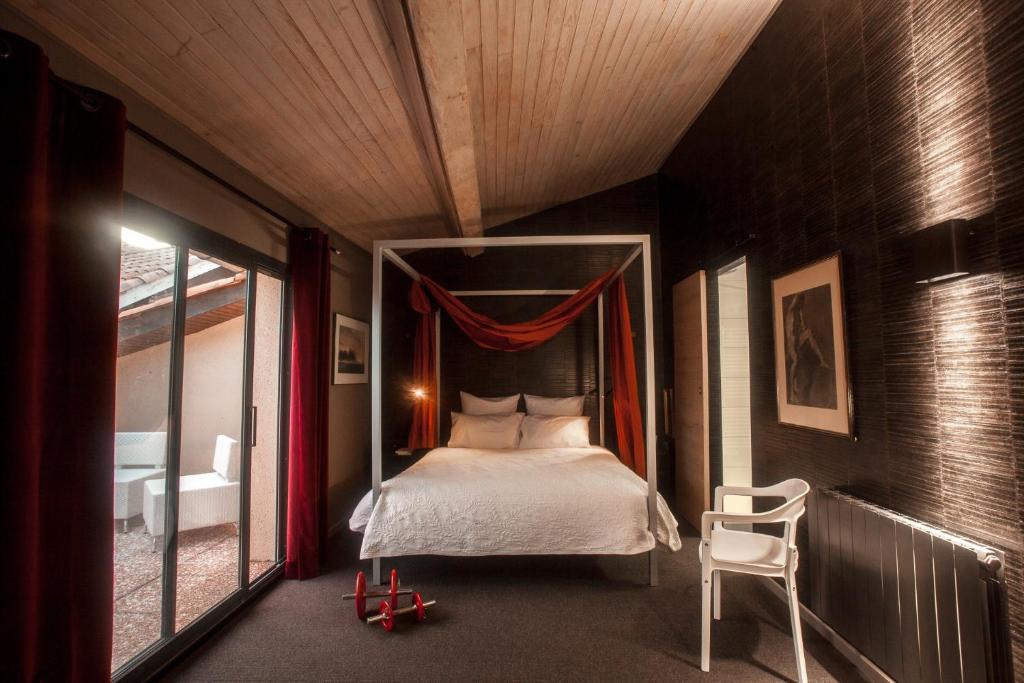 图卢兹La Closerie aux Violettes - Maison d'hôtes的一间卧室配有一张天蓬床和一把椅子