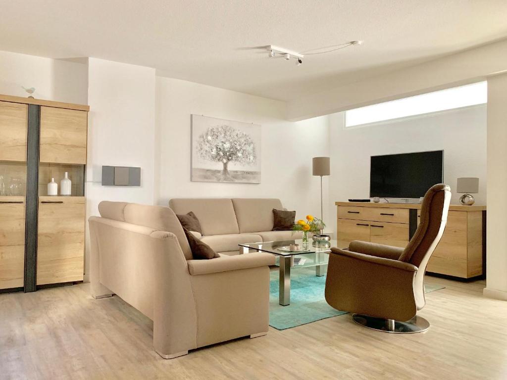 弗伦斯堡fewo1846 - Atrium - luxuriöse Wohnung mit 3 Schlafzimmern und Balkon im Stadtzentrum的客厅配有沙发、椅子和电视