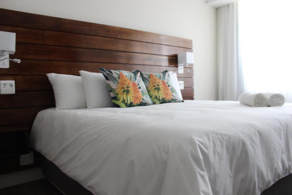 昆斯敦Luxe-Molen Boutique Hotel的卧室配有一张白色大床和木制床头板