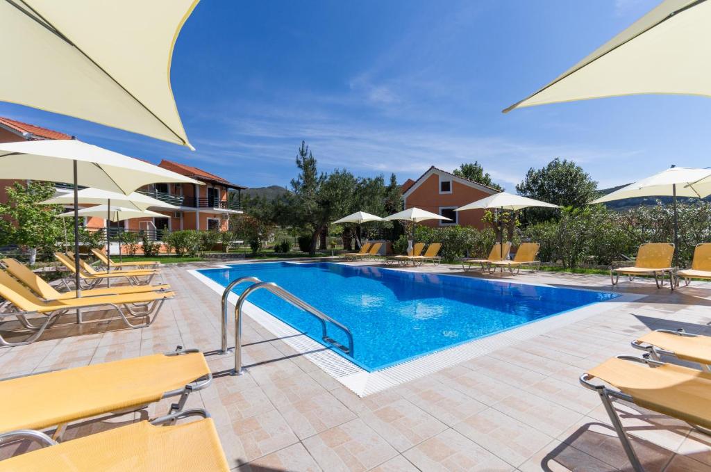 凯特利奥斯Peristera的度假村的游泳池配有椅子和遮阳伞