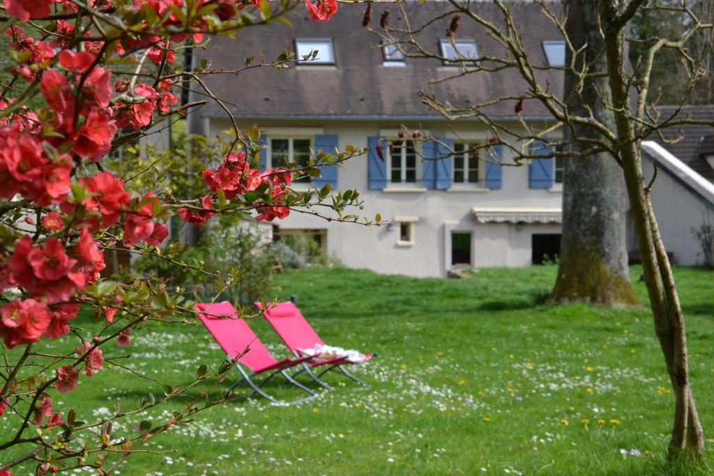 Vienne-en-Arthies维也纳阿提斯别墅住宿加早餐旅馆的坐在房子前面的草地上的粉红色椅子