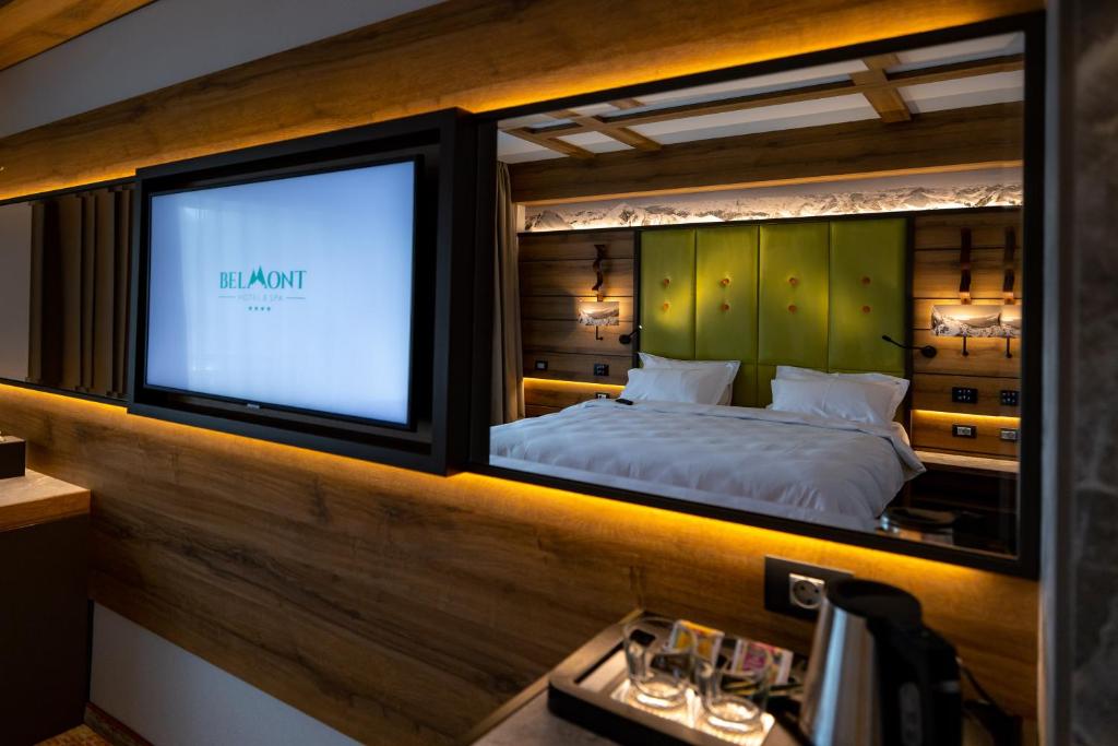 锡纳亚Hotel Belmont的一间卧室设有一张床,大窗户配有电视