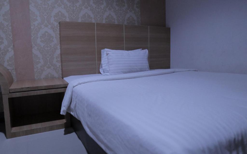 PasangkayuRedDoorz @ Pasangkayu Mamuju Utara的卧室配有白色的床和木制床头板