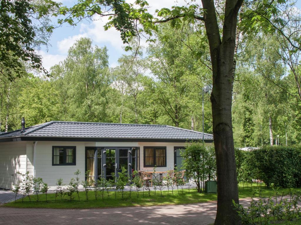 德布尔特Tidy chalet with dishwasher, surrounded by forest的一座小白色房子,有一棵树