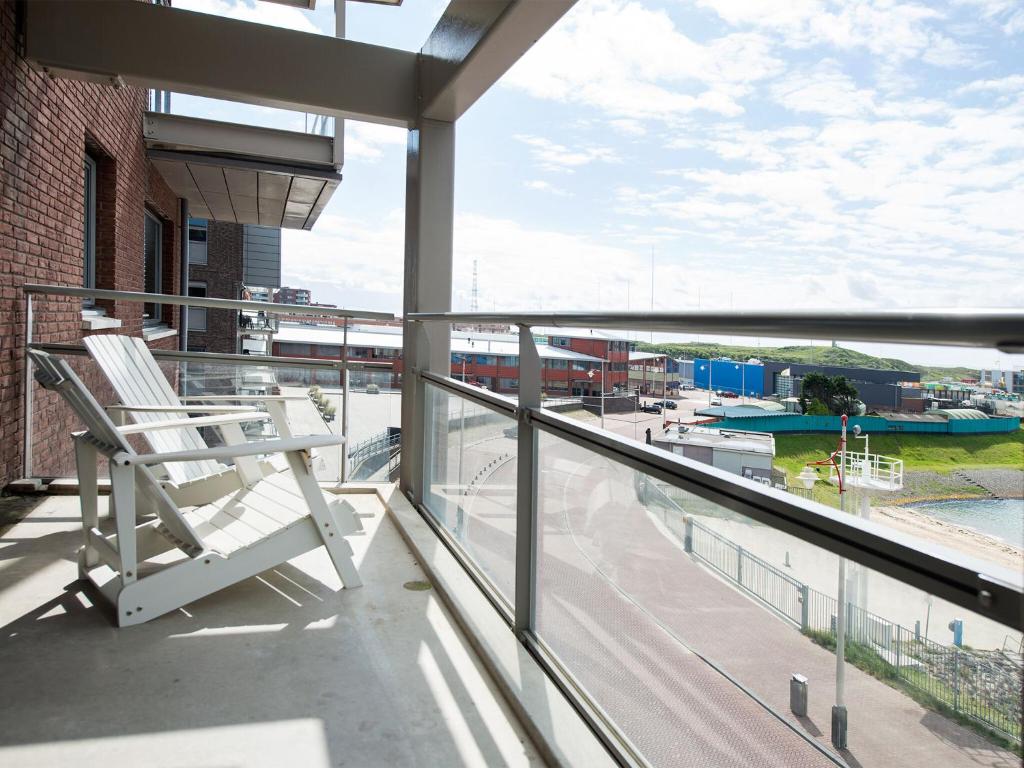 斯海弗宁恩Luxury apartment in the harbor of Scheveningen的阳台上的白色椅子享有海港景色