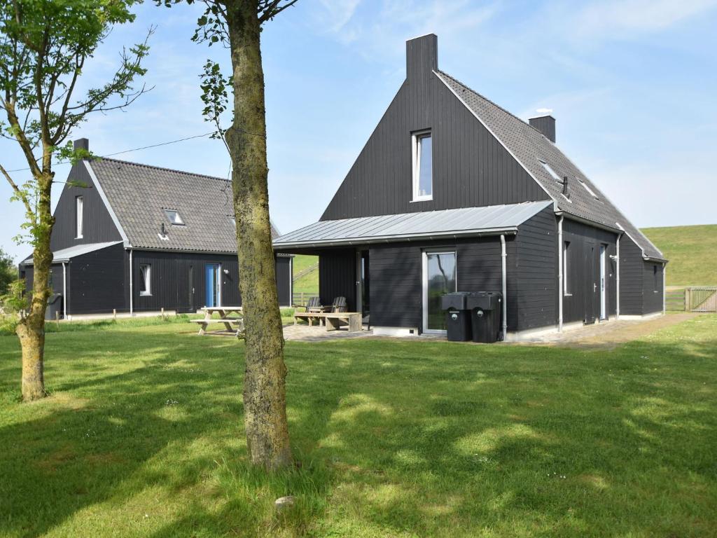 曲马勒姆Detached villa on the Zeedijk with view的前面有一棵树的黑房子