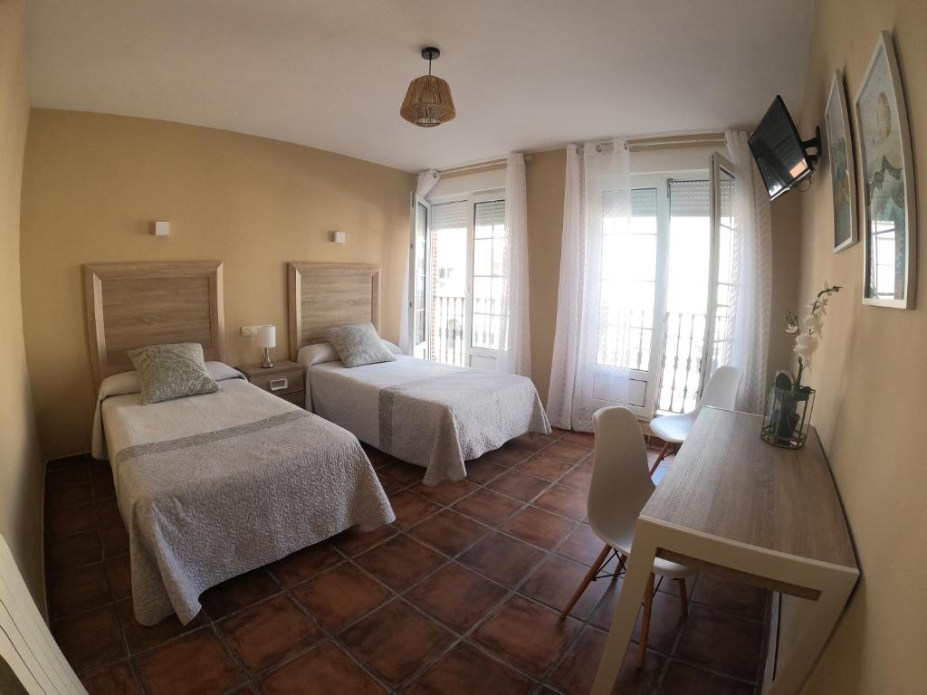 卡里翁德洛斯孔德斯Hostal Santiago的一间卧室配有两张床、一张桌子和一张桌子