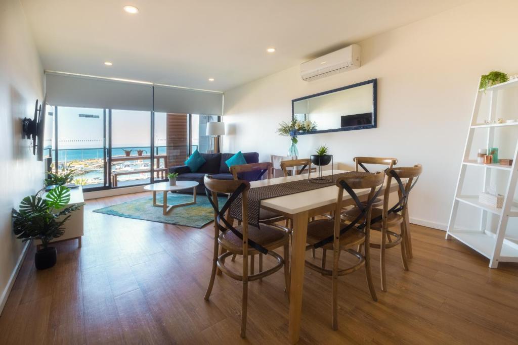 Werribee SouthWaterfront Apartments Marinaquays -Apt 221 and Apt 234的用餐室以及带桌椅的起居室。