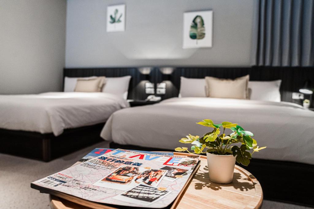 马公ZZINN,penghu的酒店客房设有两张床和一张植物桌子