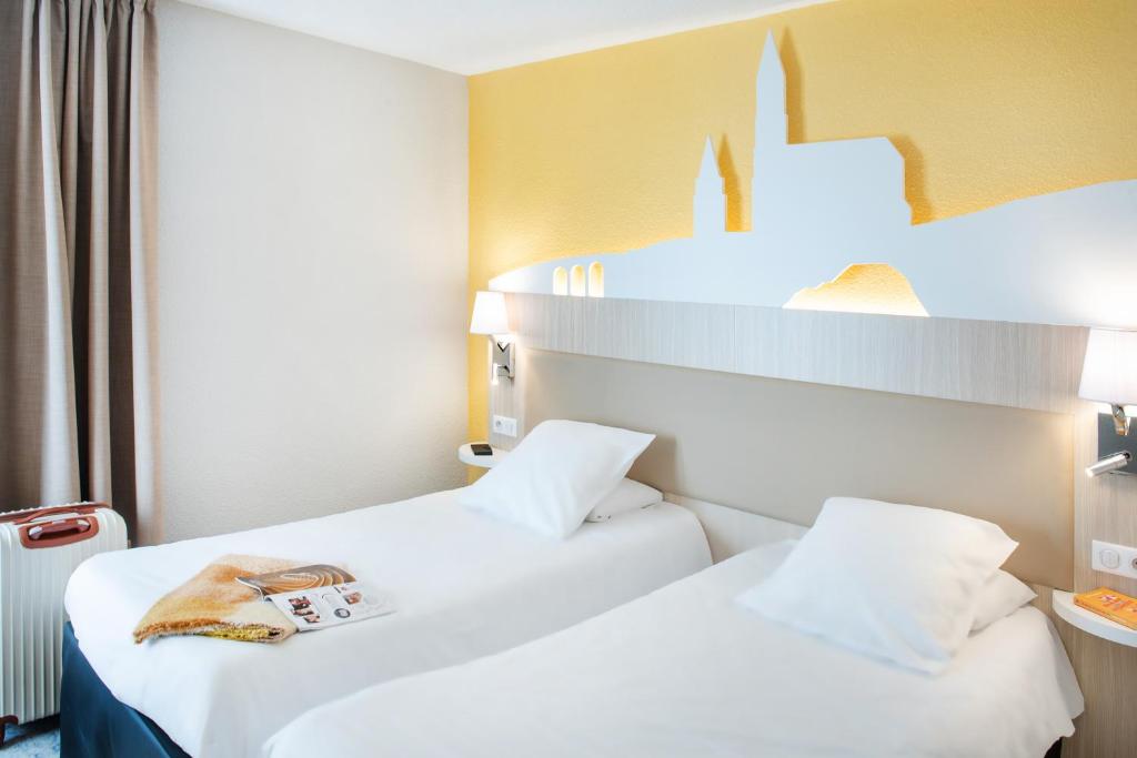 卢尔德圣索沃酒店的两张床位于酒店客房,客房顶部有钱包