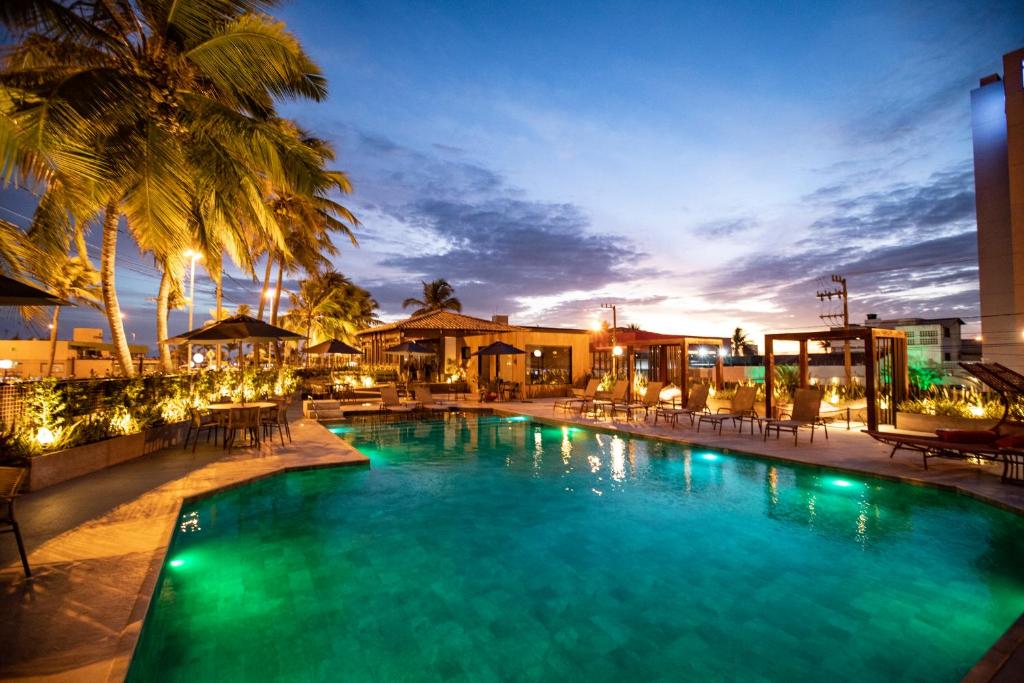 阿拉卡茹阿拉卡茹兹力酒店的游泳池在晚上设有椅子和棕榈树