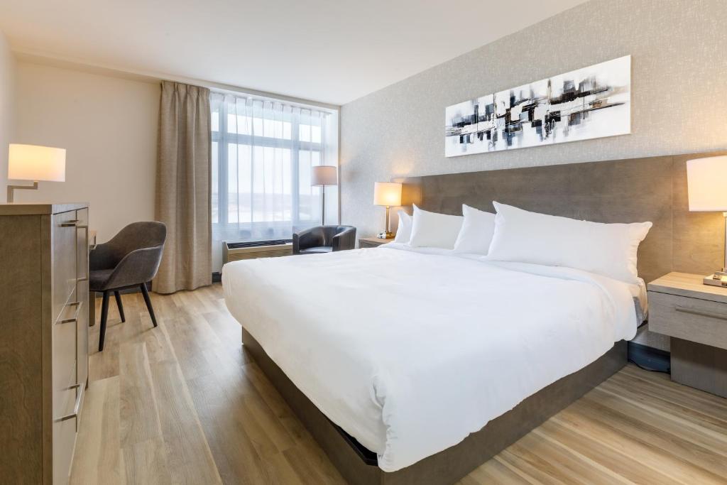 魁北克市Repotel Aéroport Québec的酒店客房设有一张白色大床和一张书桌
