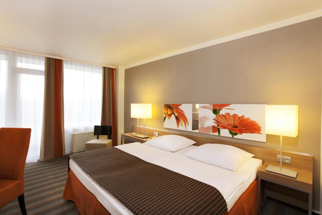 美因河畔法兰克福H4法兰克福展览中心酒店的酒店客房设有一张大床和两盏灯。